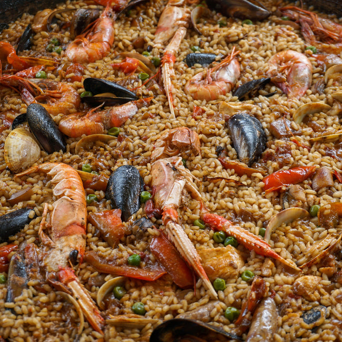 View of a paella featuring langoustines, mussels, and peas.