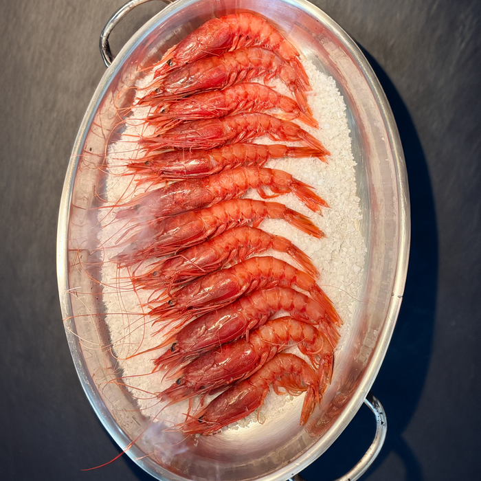 red large prawns on a bed of salt in a roasting pan on a dark slate surface