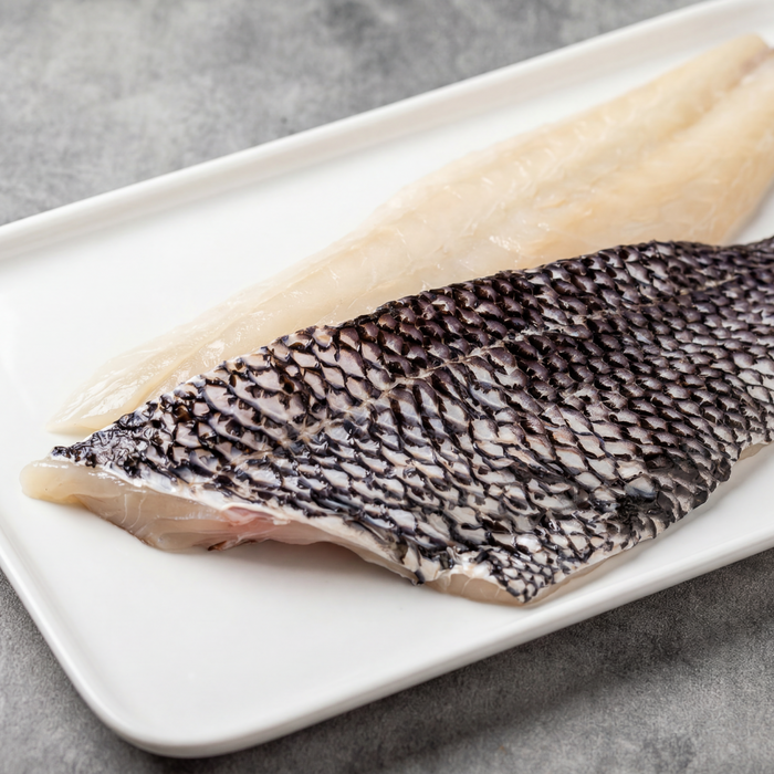 Black Sea Bass fillets from Browne Trading Company displayed on a white plate, showcasing fresh, flaky seafood.