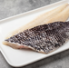 Black Sea Bass fillets from Browne Trading Company displayed on a white plate, showcasing fresh, flaky seafood.