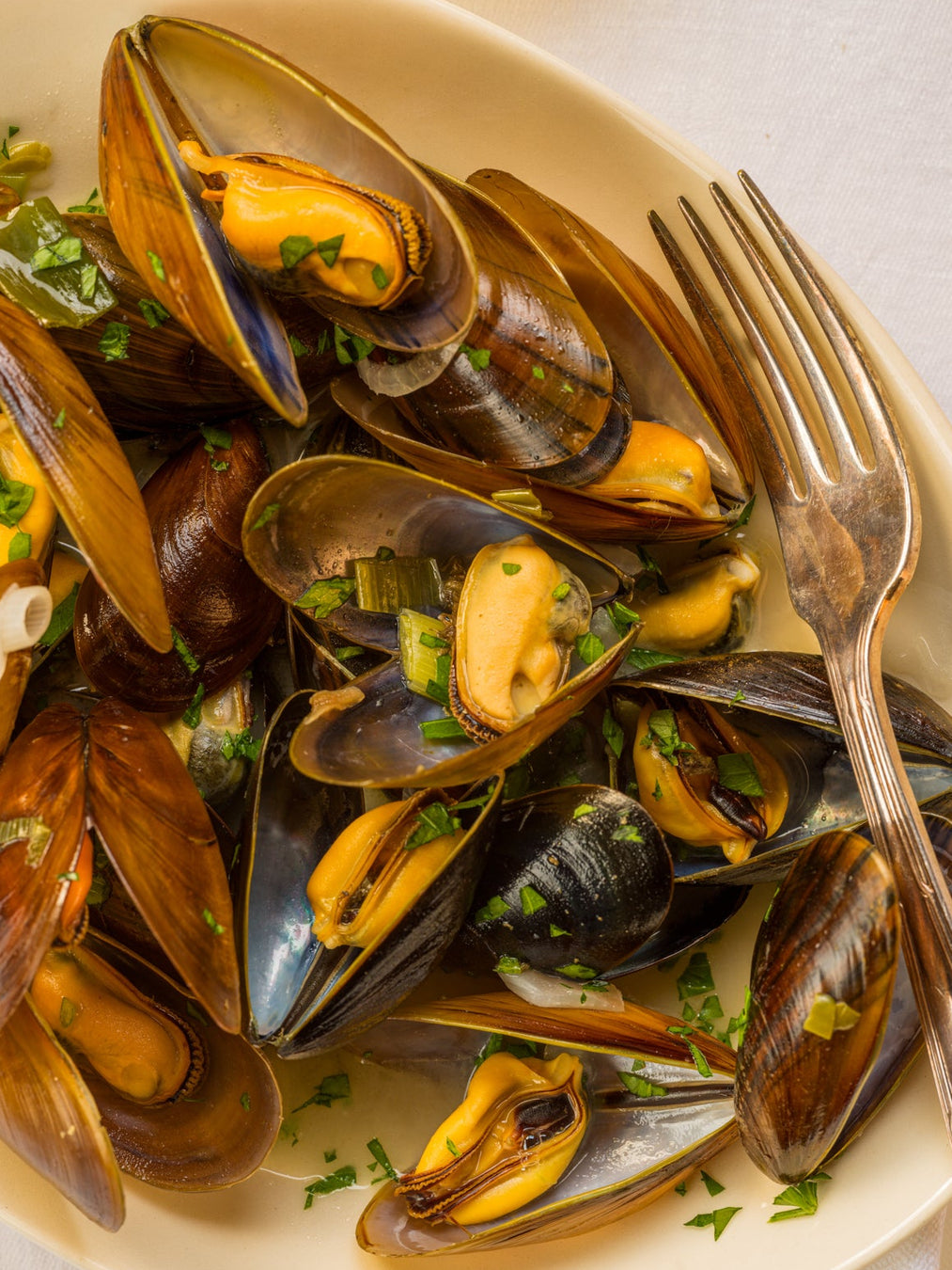 Mussels with herbs on a white plate with a fork