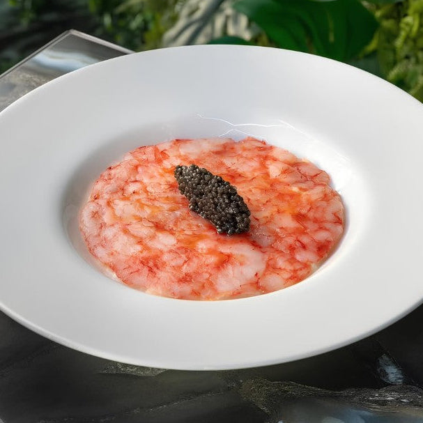 Thinly sliced Gambero Rosso prawn carpaccio from Browne Trading Company, arranged on a plate with garnishes.