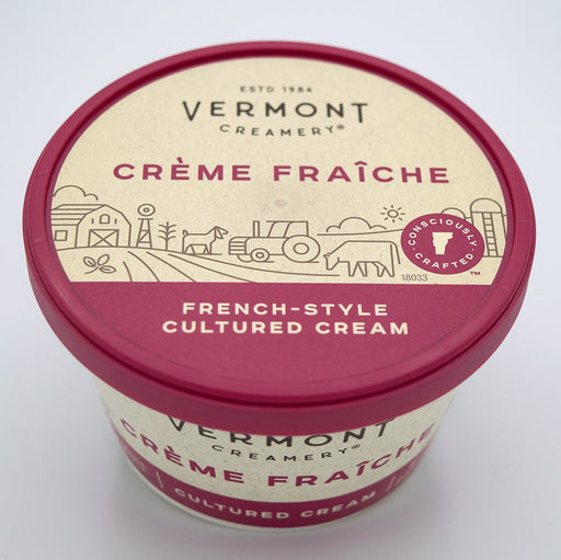 Container of Vermont Creamery Crème Fraîche French-style cultured cream with a red lid and simple farm-themed illustrations on the label.