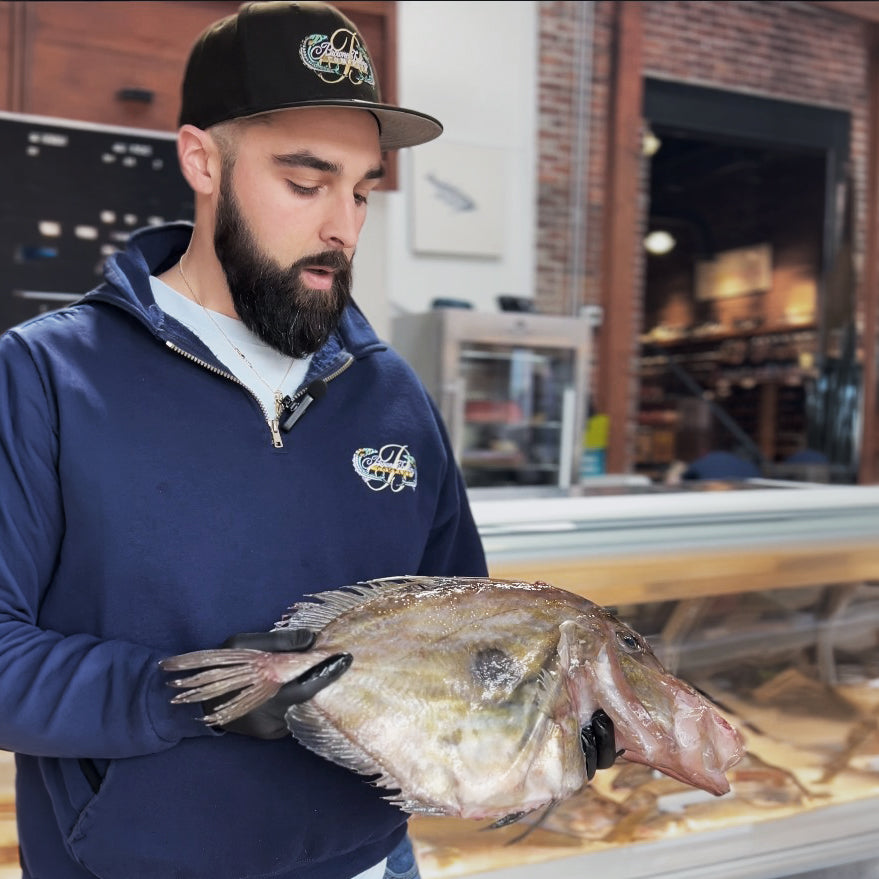 Man holding a large John Dory in a market setting