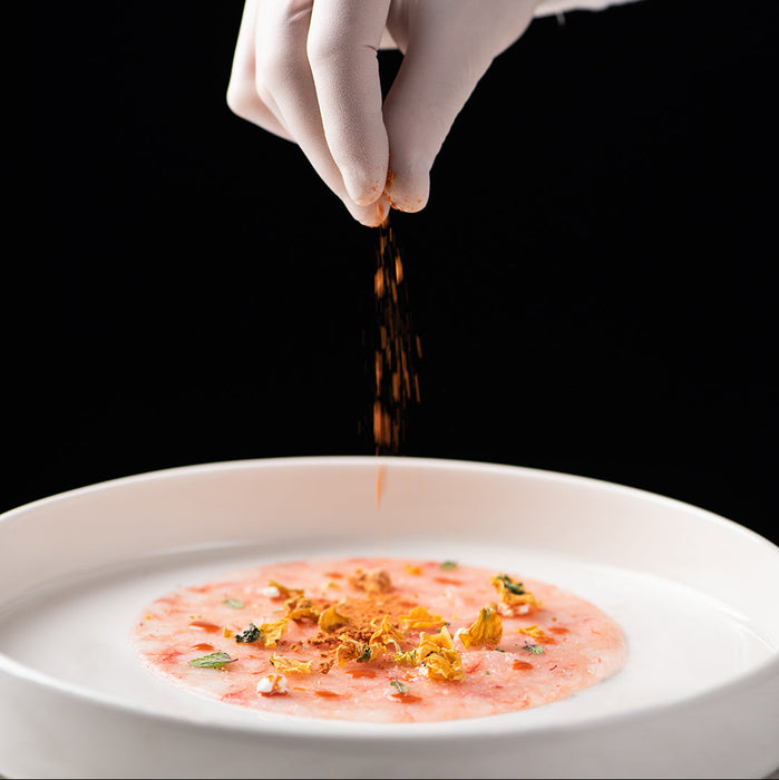 Thinly sliced Gambero Rosso prawn carpaccio from Browne Trading Company, showcasing delicate seafood on a white plate.