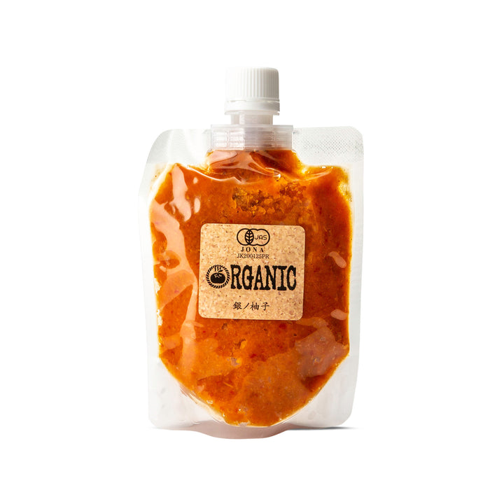 A clear plastic squeeze pouch with a white cap containing a brown-orange organic paste, featuring a beige label that reads 'ORGANIC' and 'ZOUX'.