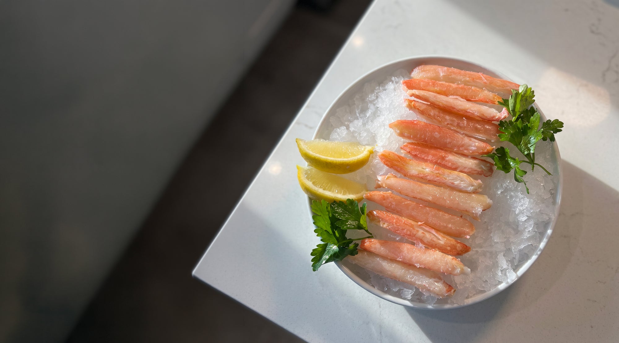 snow crab legs merus cut on a plate with ice, lemon , and parsley