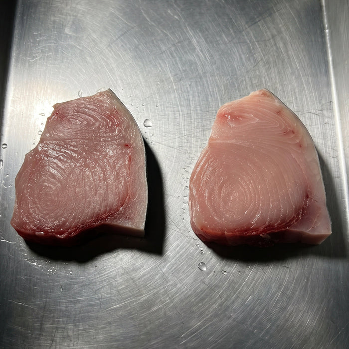 Two pieces of raw swordfish on a metallic tray