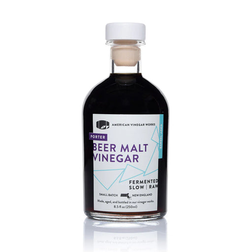 A bottle of Porter Beer Malt Vinegar on a white background with a reflection of the bottle below. The glass bottle has a white cap, a cork stopper, and a white label with purple and light blue text and graphics.