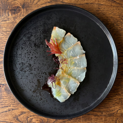 Dry Aged Madai sliced into seven pieces of crudo, garnished with seaweed