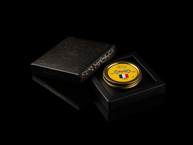 Elegant French Gift Box with a gold tin of Sturia Premier Osetra, featuring a French flag, presented in a black box with gold floral design on a black background