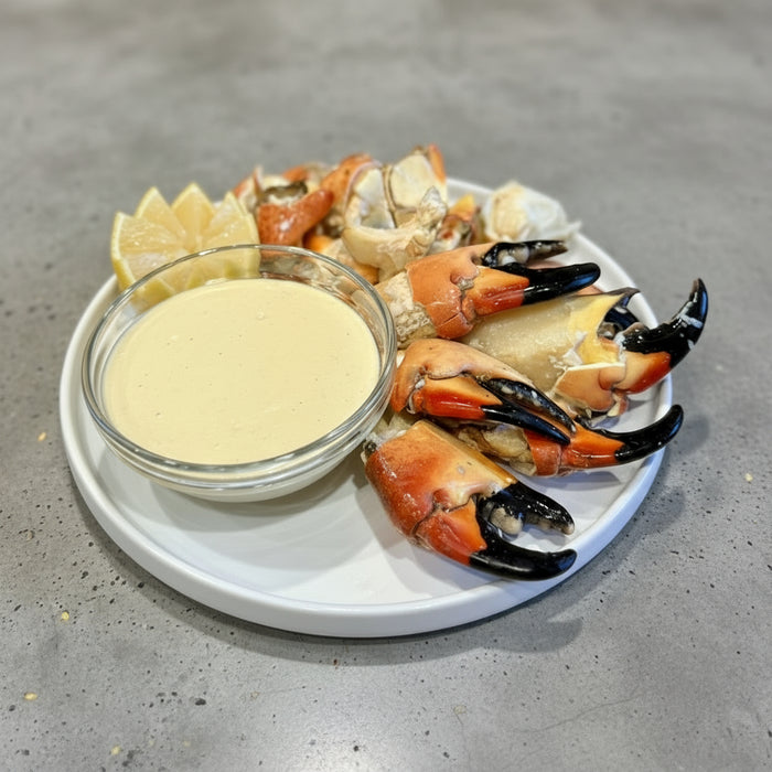 Plated stone crab claws with a side of aioli on a wooden table